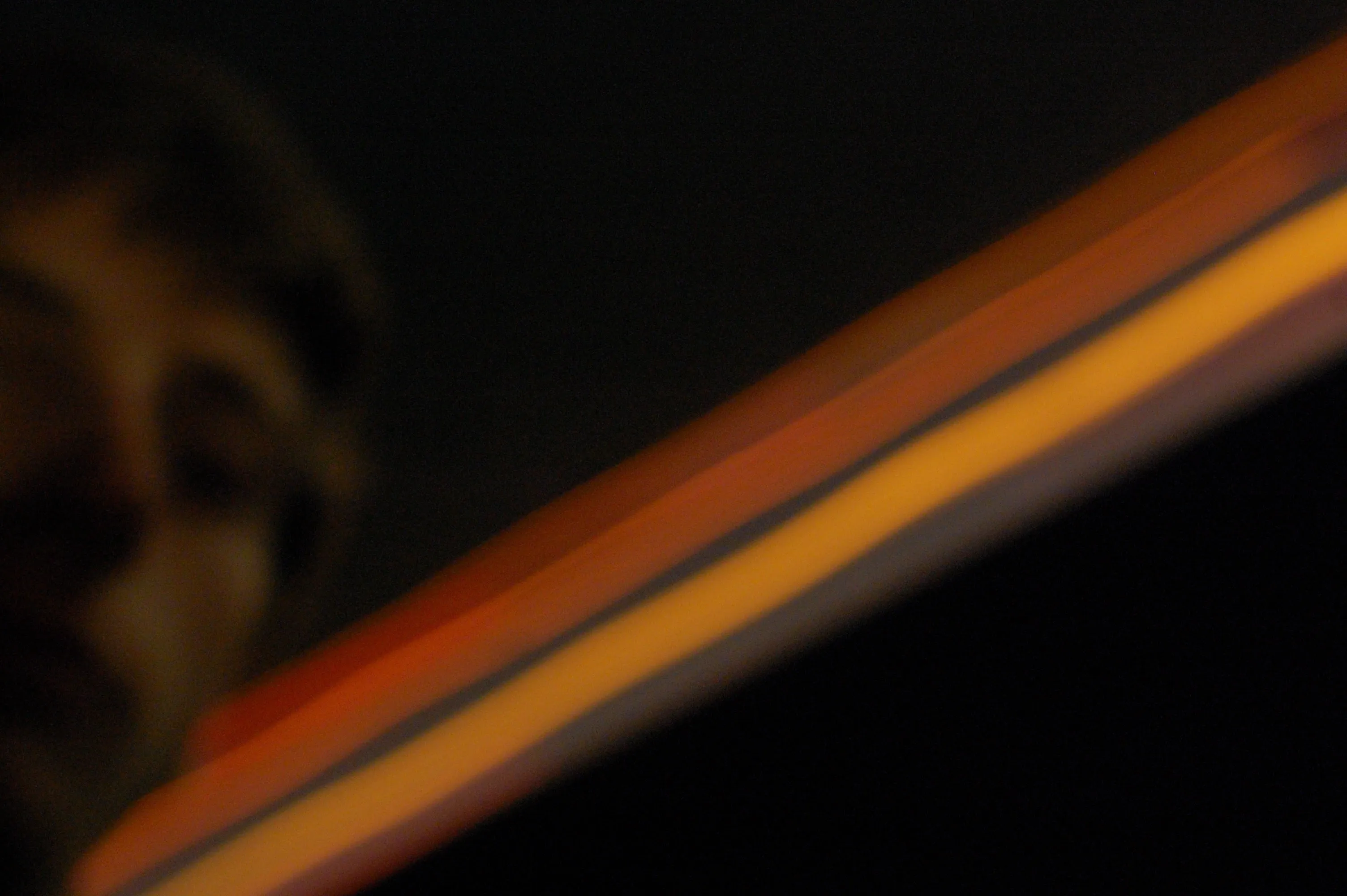 blurry headlights streak from left to right; my blurry face is cut-off in the corner